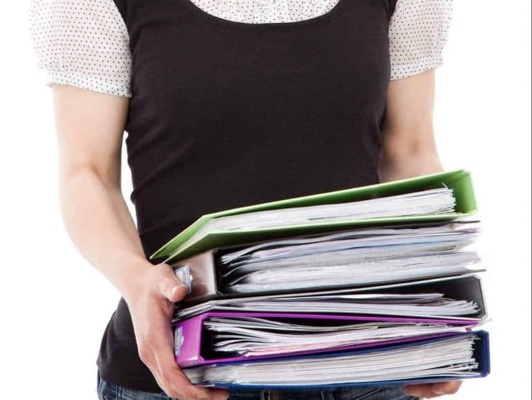 Person holding stack of colorful folders.