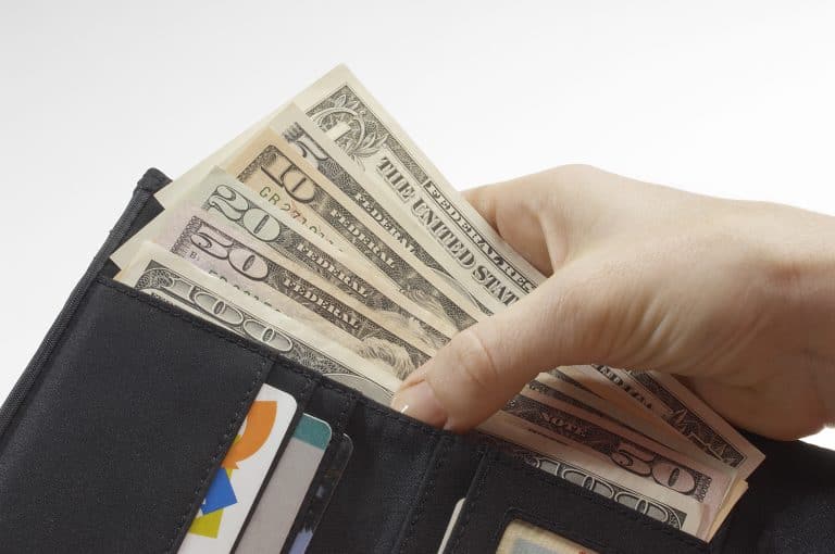 Hand holding US dollars in wallet.