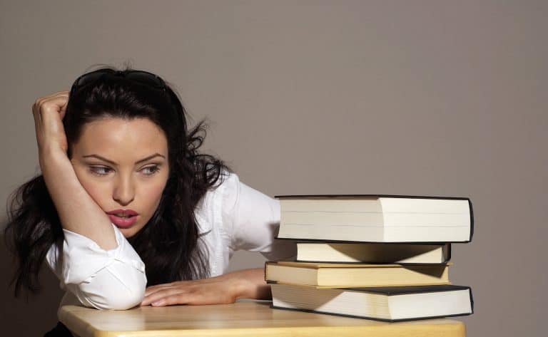 Woman with books, looking thoughtful and contemplative.