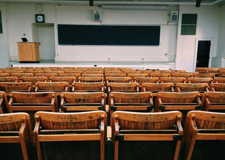 Empty classroom with wooden chairs and chalkboard.