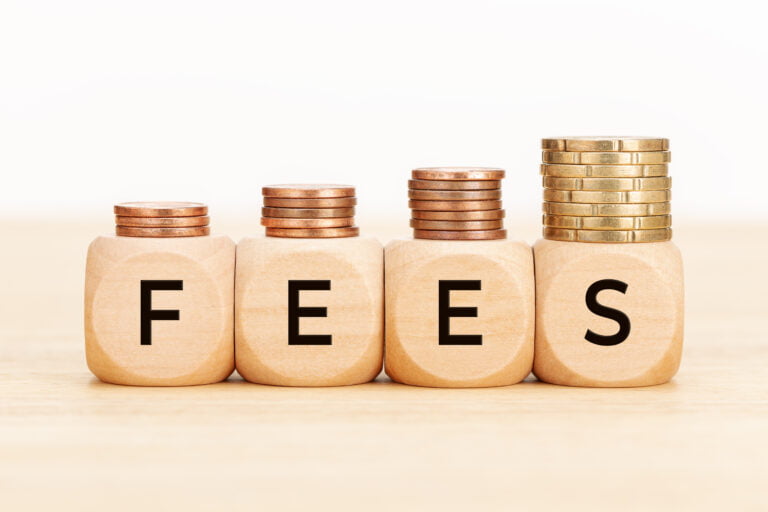 Fees concept with stacked coins on blocks.