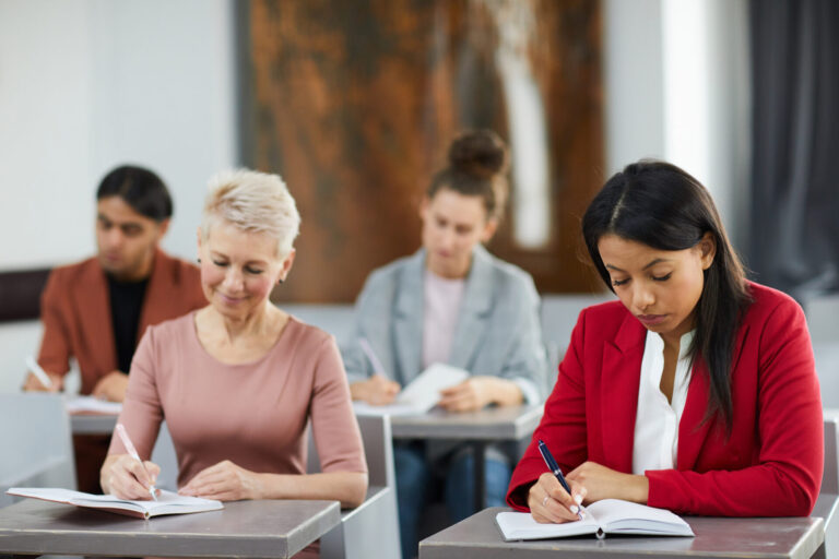 Women writing in classroom setting.