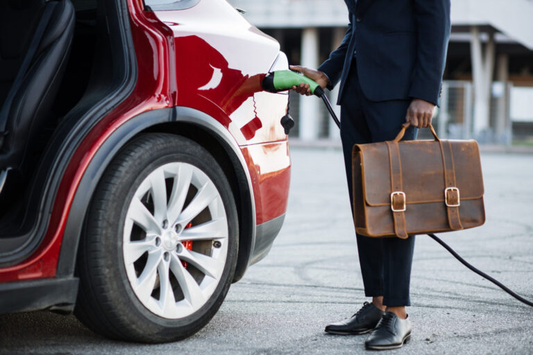 Person charging electric car with briefcase