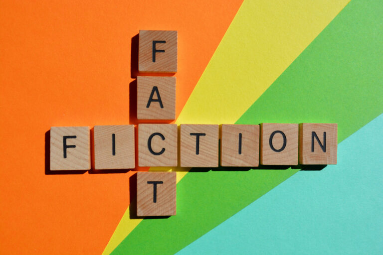 Blocks spell Fact and Fiction on rainbow background.