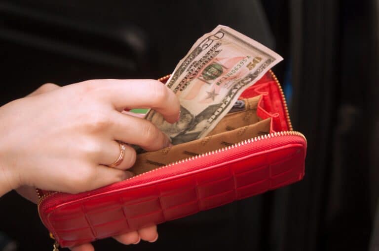 Hand holding cash in red wallet