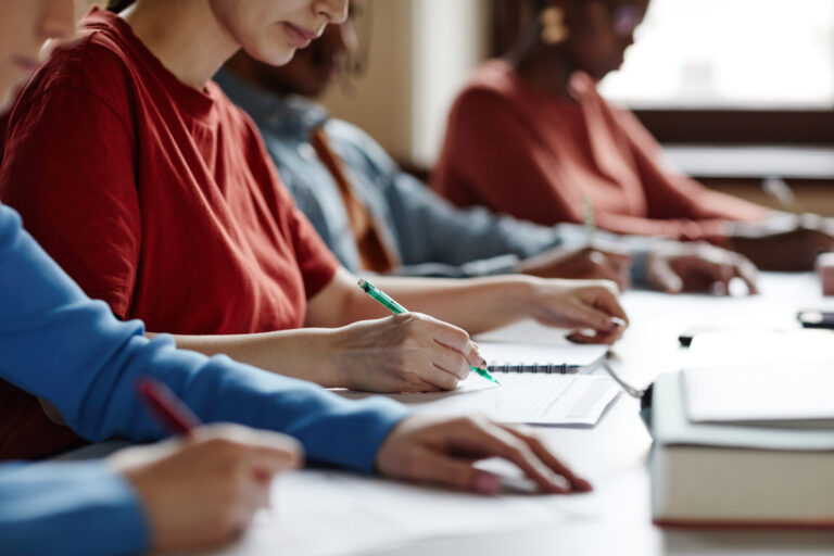 People writing notes in a classroom setting.