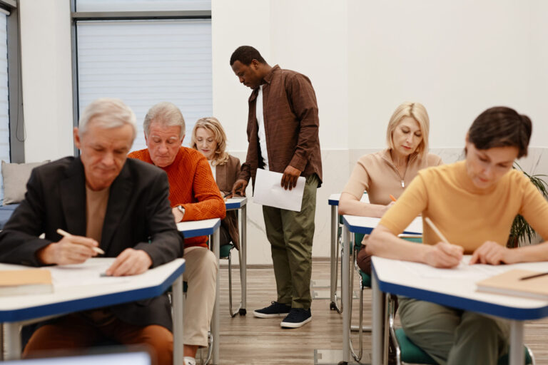 Mature students taking test in classroom setting.