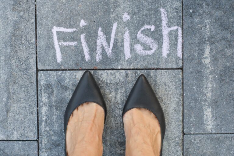 Shoes at chalk finish line on pavement.